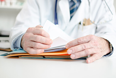 Doctor in lab coat looking at a file.