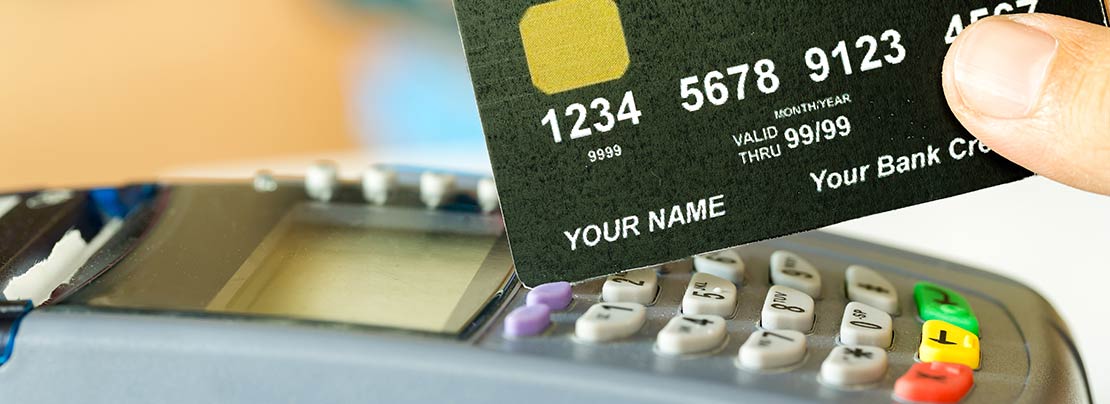 Person holding a credit card at a processing terminal.