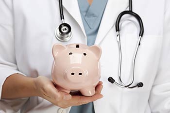 Doctor holding a piggy bank representing saving money on our Employee Wellness Program located in our Boise, Garden City, Meridian, Nampa, Idaho Falls, Pocatello and Rexburg areas.