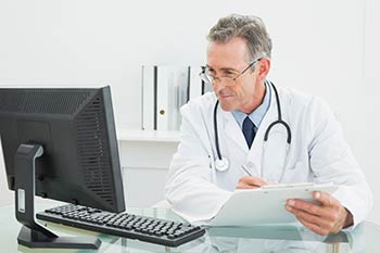 Physician looking at computer to download lab requisitions for our Boise, Garden City, Meridian, Nampa, Idaho Falls, Pocatello and Rexburg locations.