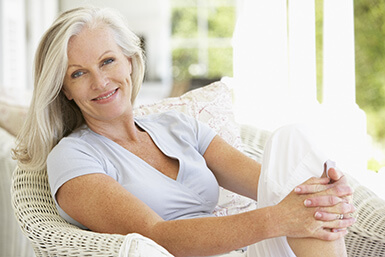 Senior woman sitting in chair, smiling.