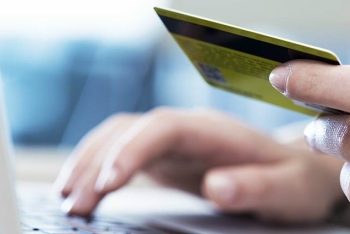 Woman with credit card entering data into laptop computer.