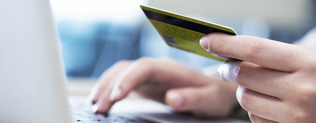 Woman holding a credit card, entering information into a computer.