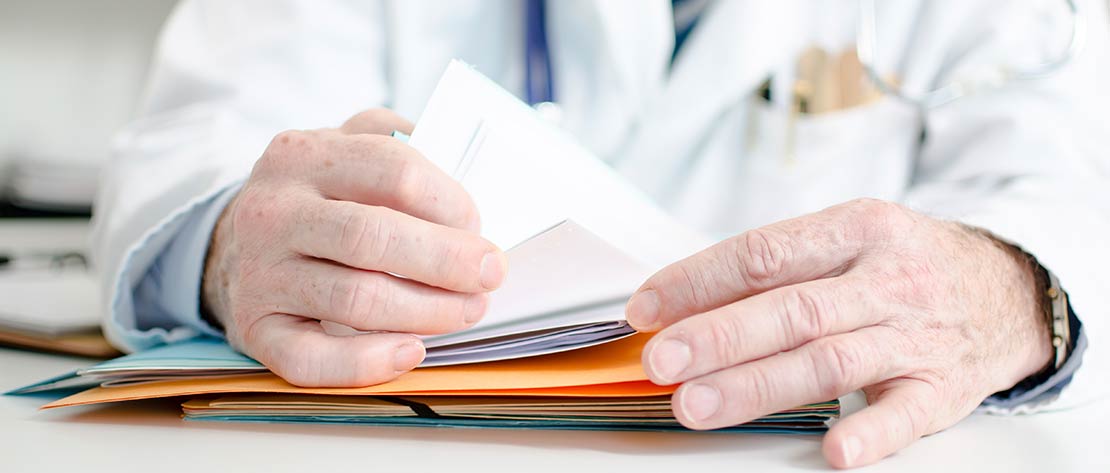 Doctor reviewing a patient file from Express Lab, a medical laboratory, with draw site locations in Boise, Garden City, Meridian, Nampa, Pocatello, Idaho Falls and Rexburg.