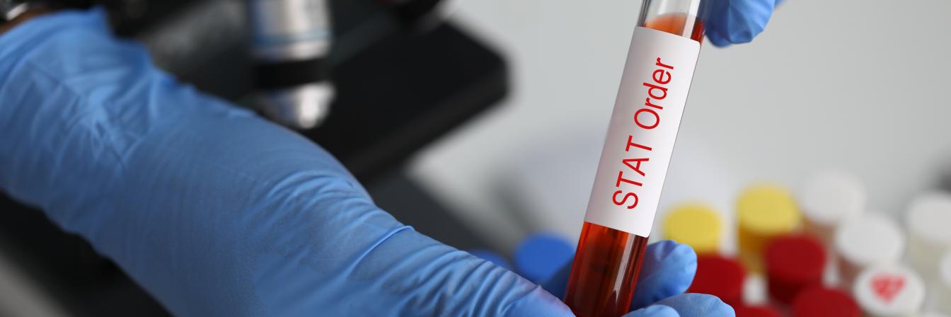 Medical lab stat testing underway. A lab technician with a blood sample labeled "STAT Order" in the medical lab STAT testing process.